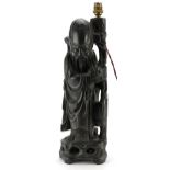 Chinese root wood lamp base carved in the form of an elder holding a staff and fruit, 49cm high