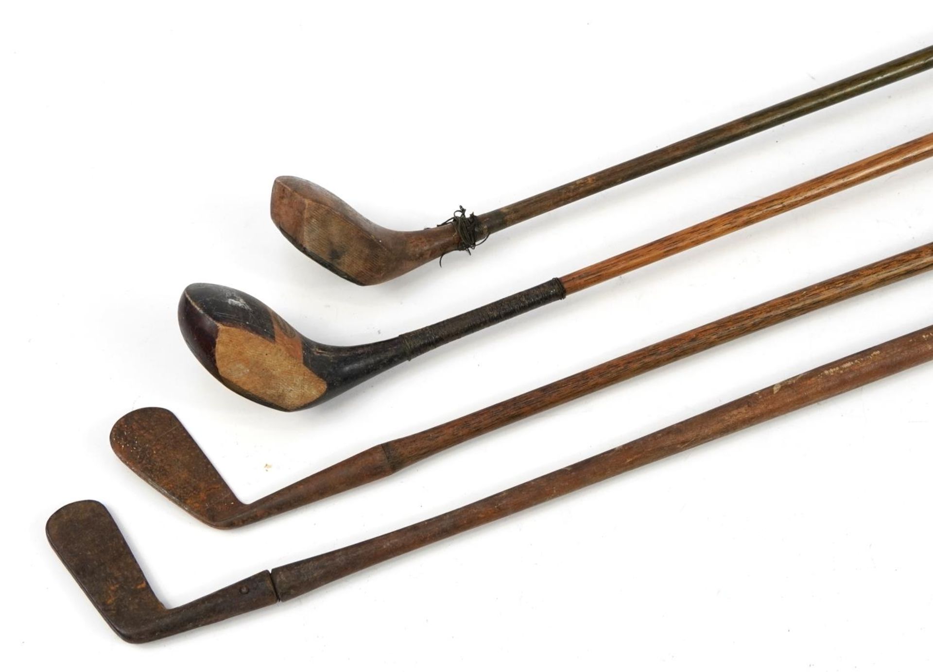 Four early 20th century wooden shafted golf clubs, the largest 109cm in length