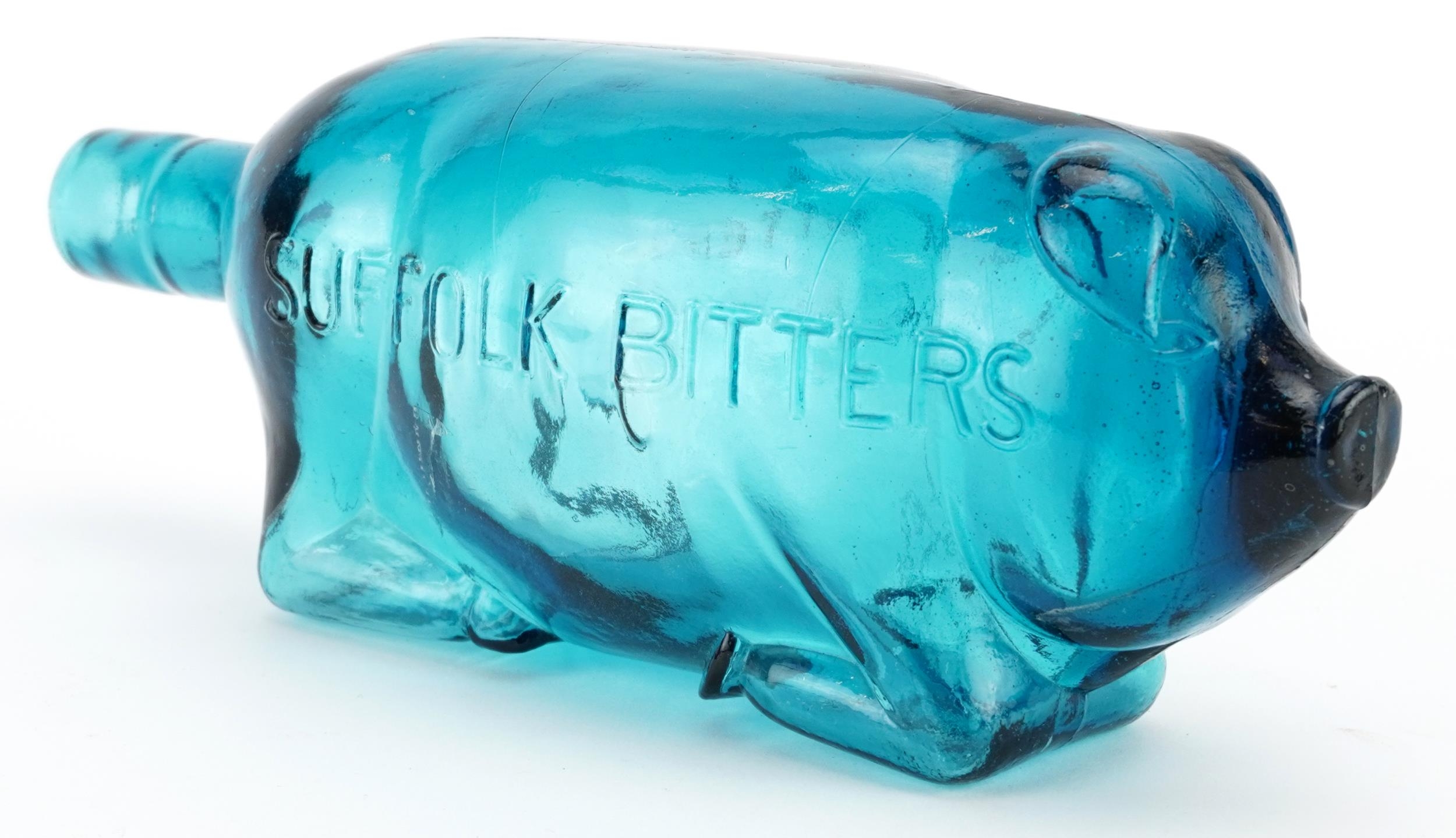 Blue glass bottle in the form of a pig advertising Suffolk Bitters, 24cm in length