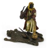 Modern cold painted bronze of an Arab holding an animal skull on a bearskin rug in the style of