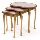 Nest of three kidney shape occasional tables with tooled leather tops and glass inserts, the largest
