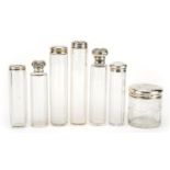 Seven Edwardian and later cut glass jars with silver lids, some with embossed decoration, various