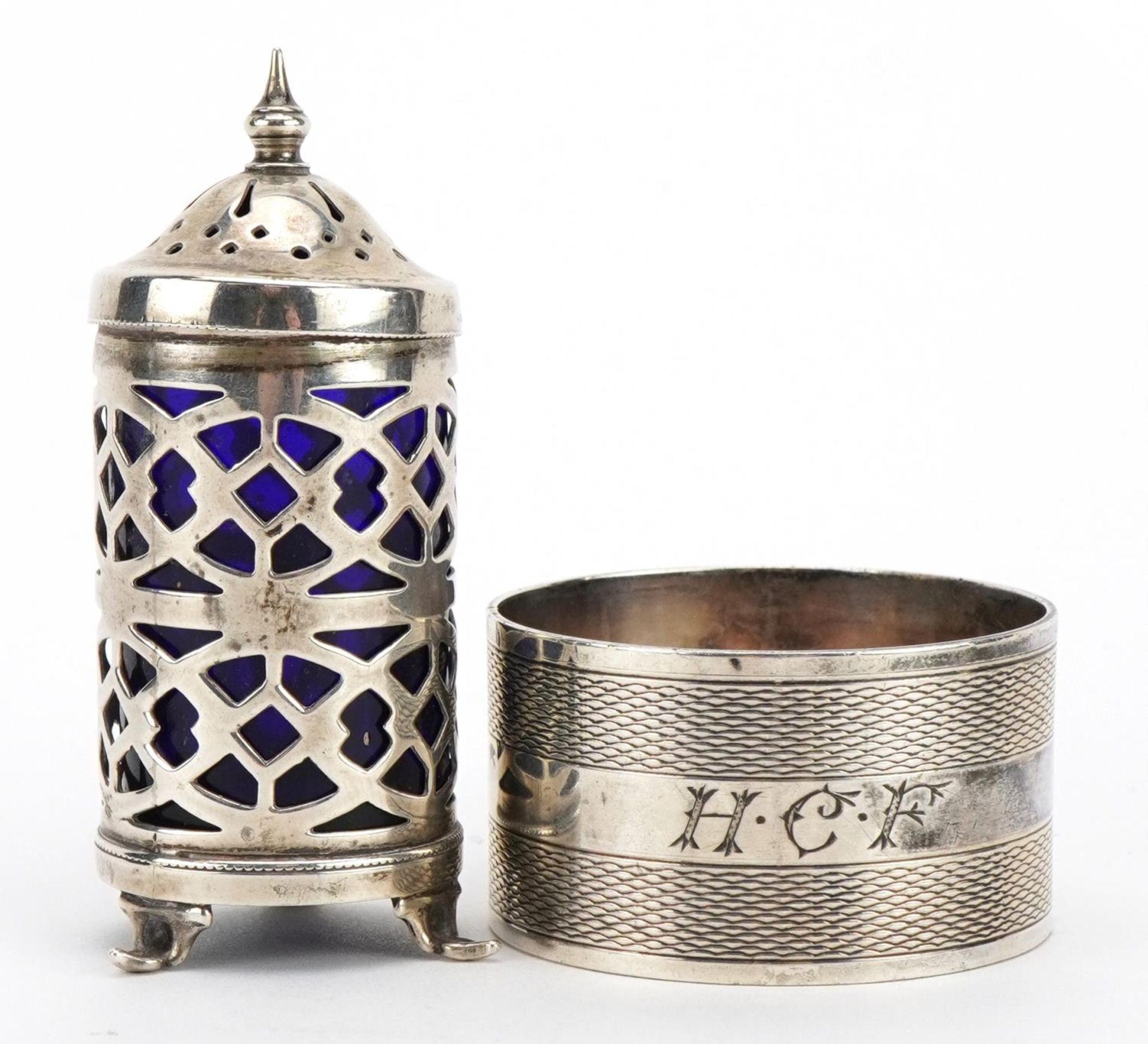 Circular silver napkin ring with engine turned decoration and a silver caster with blue glass liner,