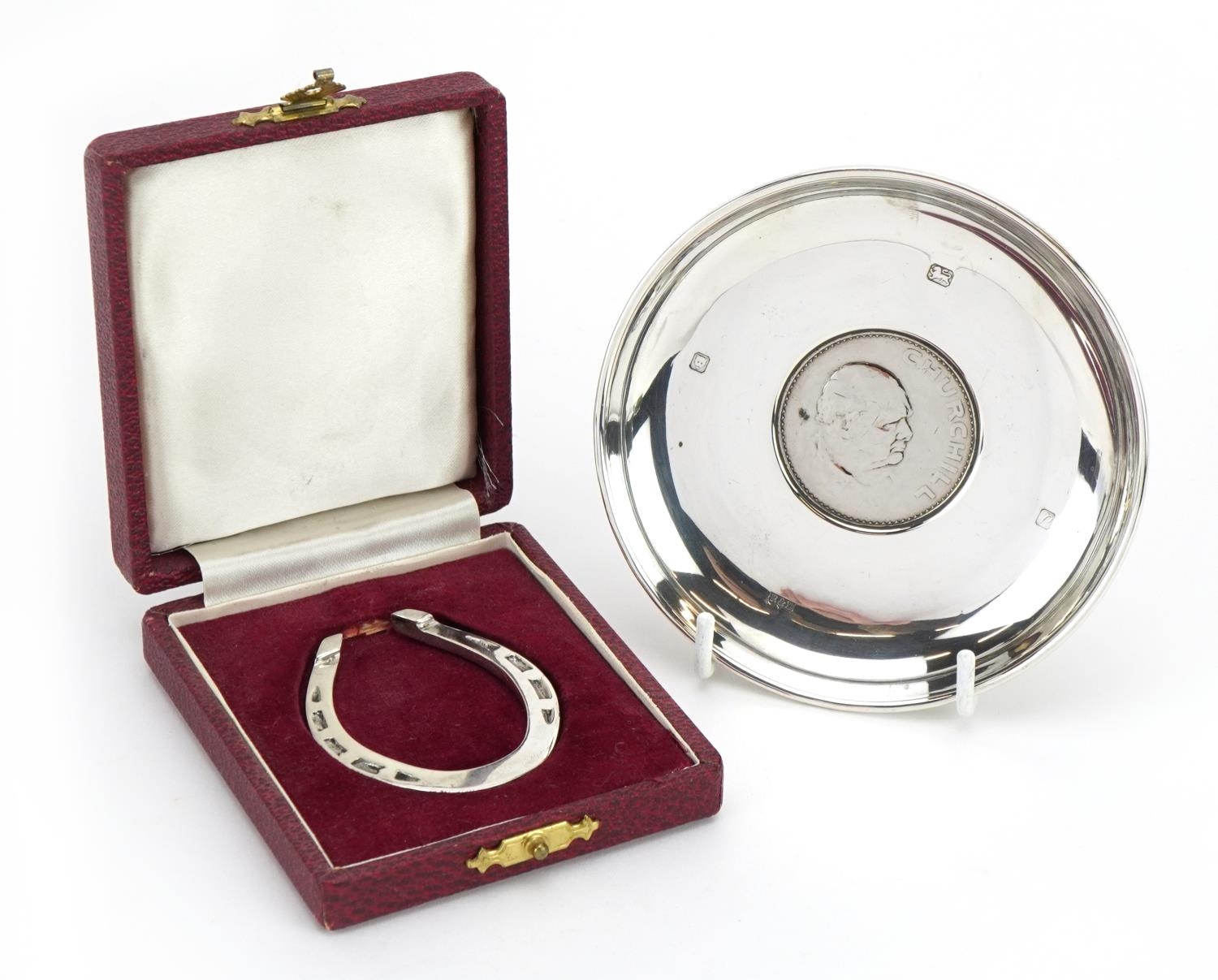 Circular silver commemorative dish set with a 1965 Churchill crown and a silver horseshoe napkin