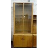 A modern Ercol light elm display cabinet, the upper section fitted with a pair of glazed doors and