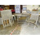 A weathered teak circular slatted-top patio table, 125cm diameter and four matching folding chairs.