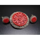 An Eastern cinnabar lacquer panel and plated filigree circular brooch, 43mm diameter, with