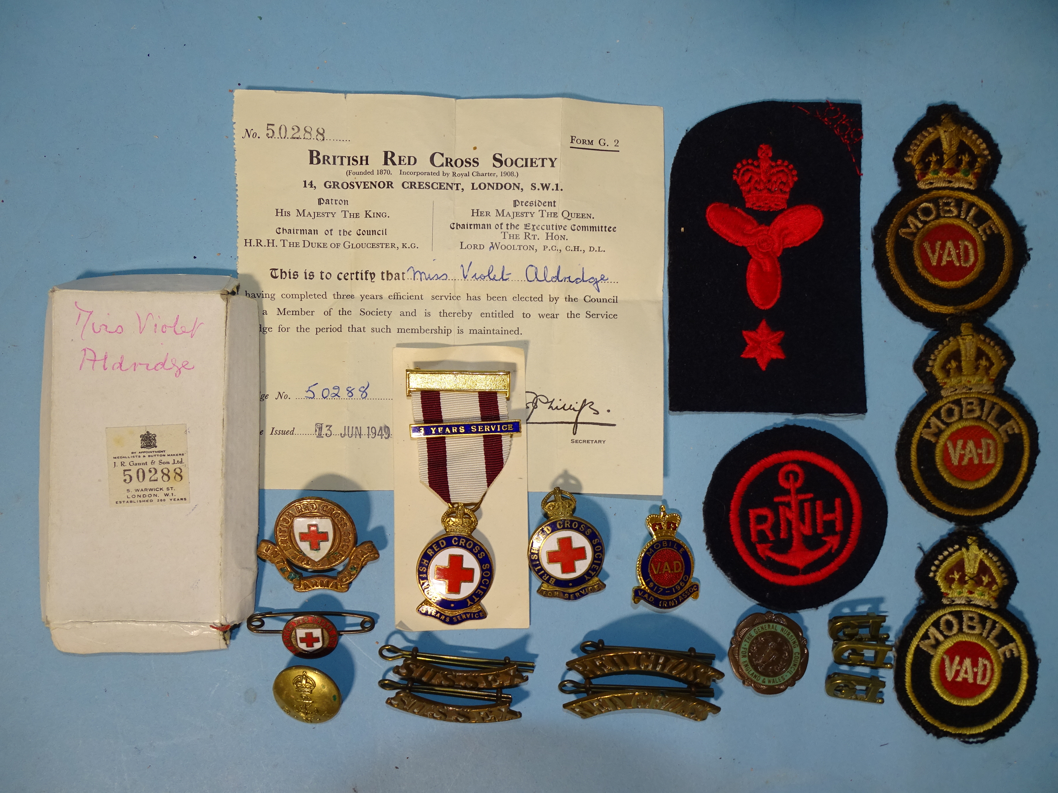 A British Red Cross Society three years service medallion and various metal and cloth badges for VAD