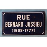 A French enamelled road sign "Rue Bernard Jussieu (1699-1777)", white font on blue background, 25