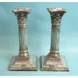 A pair of Edwardian silver Corinthian column candlesticks on loaded square bases by J Sherwood &