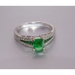 A tsavorite and diamond ring claw-set a square-cut tsavorite of approximately 0.8cts, between
