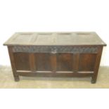 An antique oak panelled coffer, the hinged lid above a carved frieze and styles extended to form