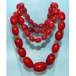 A necklace of very large cherry amber Bakelite type beads, largest 39mm long, 27mm diameter,