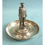 A circular silver pin tray with central mounted figure of a soldier at ease, holding a rifle with
