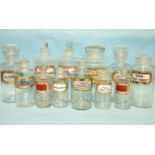 Twelve apothecary clear glass jars with stoppers and lids, various shapes, mainly recessed gilt