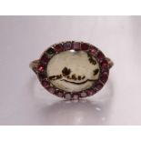 A Georgian moss agate ring set oval agate panel within border of closed-back stones, (one missing,