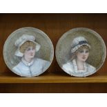 A pair of Derby ceramic plates, each painted with a portrait of a young woman wearing a mob cap,