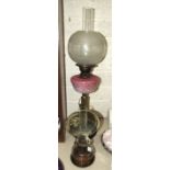 A late-Victorian oil lamp, the pink opaque glass reservoir with painted enamel floral decoration, on
