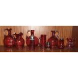 A cranberry glass sugar sifter, 14.5cm high, two jugs and six other pieces of cranberry glass, (9).