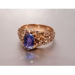 A yellow metal ring claw-set an oval violet natural sapphire of approximately 1.6cts, between chased