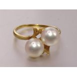 A crossover ring set two cultured pearls, the mount marked 'K18', size O½, 3.7g.