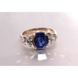 A sapphire and diamond ring claw-set an oval sapphire of approximately 2.3cts between triplets of