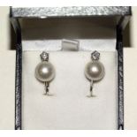 A pair of 18ct white gold pearl and diamond earrings, each earring set with a single pearl of