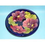 A Moorcroft bowl with clematis decoration on a blue ground, impressed factory mark and painted