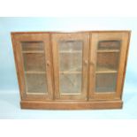 An Edward Barnsley oak bookcase of slightly chamfered form fitted with three glazed doors, one