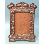 An Art Nouveau silver photograph frame of shaped rectangular form, with embossed decoration of