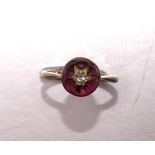 A Victorian 9ct gold ring collet-set a round garnet cabochon surmounted by an old-cut diamond-set