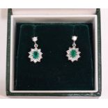 A pair of emerald and diamond cluster earrings, each claw-set an oval emerald, (approximately 5 x