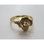 An 18ct gold ring claw-set a brilliant-cut diamond within a flower head, size N½, 3g.