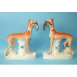 A pair of mid-19th century Staffordshire greyhound ornaments, each holding a hare in its mouth, 30cm