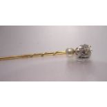 A gold stick pin claw-set a pendeloque-cut diamond of approximately 0.9cts, above a small cultured
