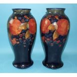 A pair of Moorcroft baluster-shaped vases, each with pomegranate decoration on a dark blue ground,