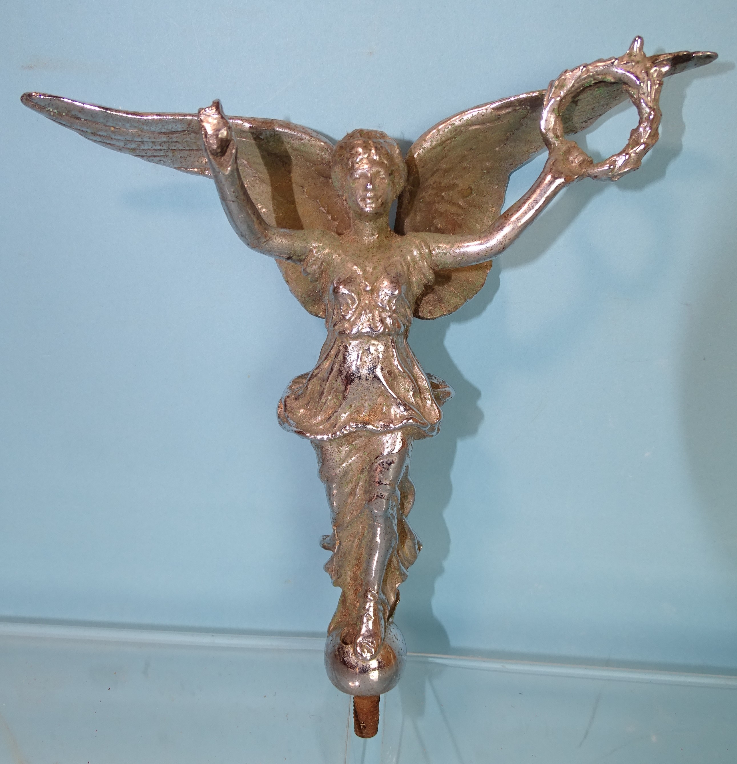 A 20th century plated car mascot in the form of a winged female figure holding a laurel wreath in