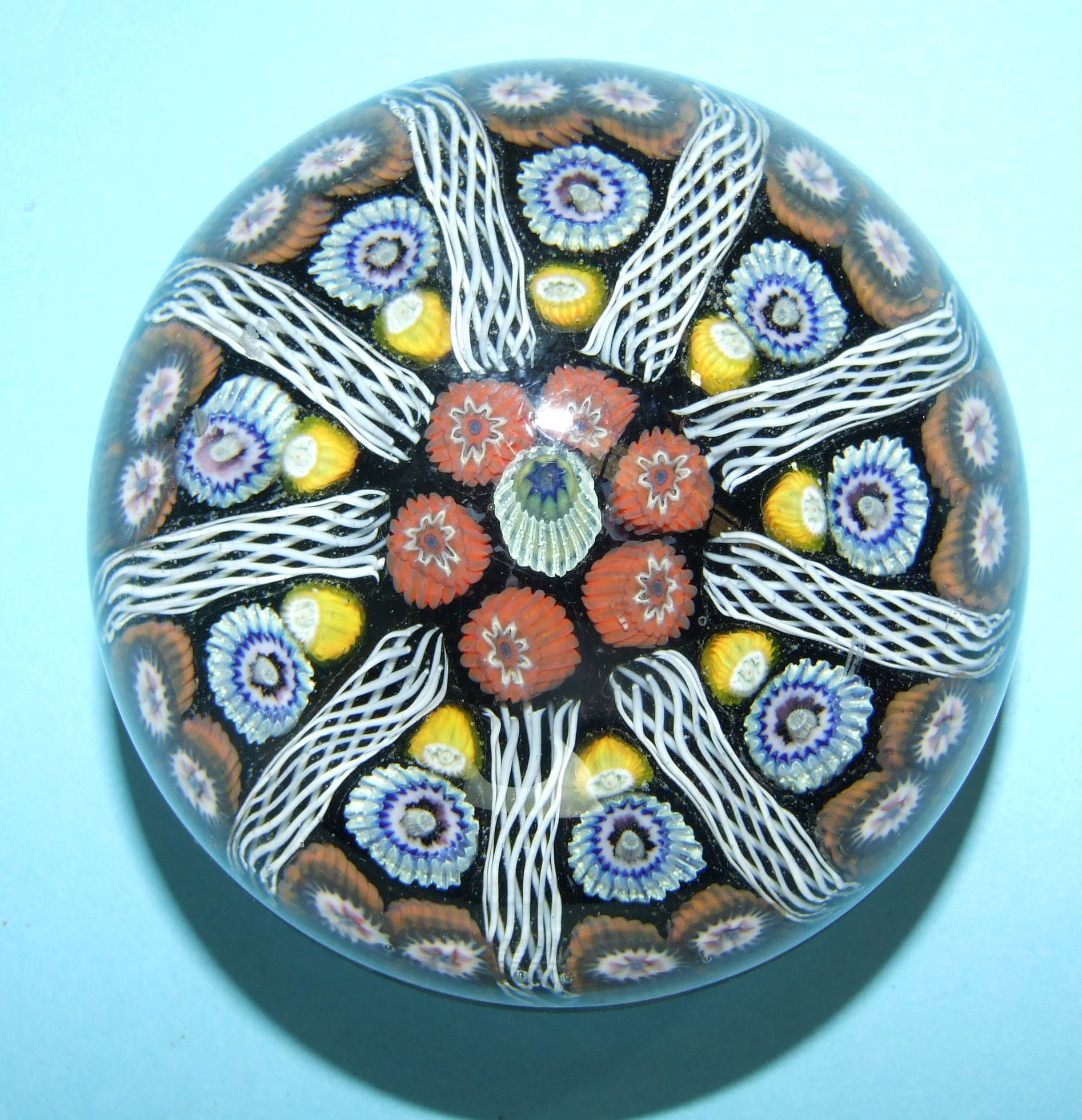 A millefiori glass paperweight, the symmetrical group of vertical multi-coloured canes divided by