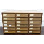 A wooden nest of eighteen drawers containing various brass and metal door furniture and fittings,