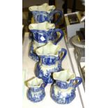 A set of five Victoria Ware ironstone graduated blue and white jugs printed with a village scene,