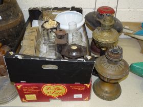 A collection of various brass and metal oil lamps, some incomplete, with spare parts, glass shades