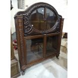 A mid-20th century Continental hardwood display cabinet, having a pair of oval glazed doors framed