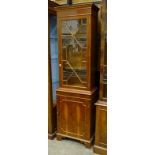 A modern yew wood narrow bookcase fitted with an astragal-glazed door above a base cupboard door,