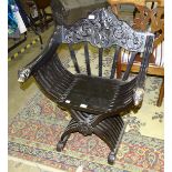 A Continental black-lacquered X-framed hall chair with lion head terminal arms.