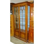 A reproduction walnut display cabinet fitted with a pair of glazed doors and three adjustable