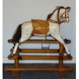 An early-20th century rocking horse of painted plaster and wood construction, on pine trestle frame,