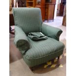 An Edwardian deep-seated armchair on turned front legs with castors.