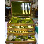 A part-canteen of plated cutlery contained in an inlaid wood cabinet with three fitted drawers and