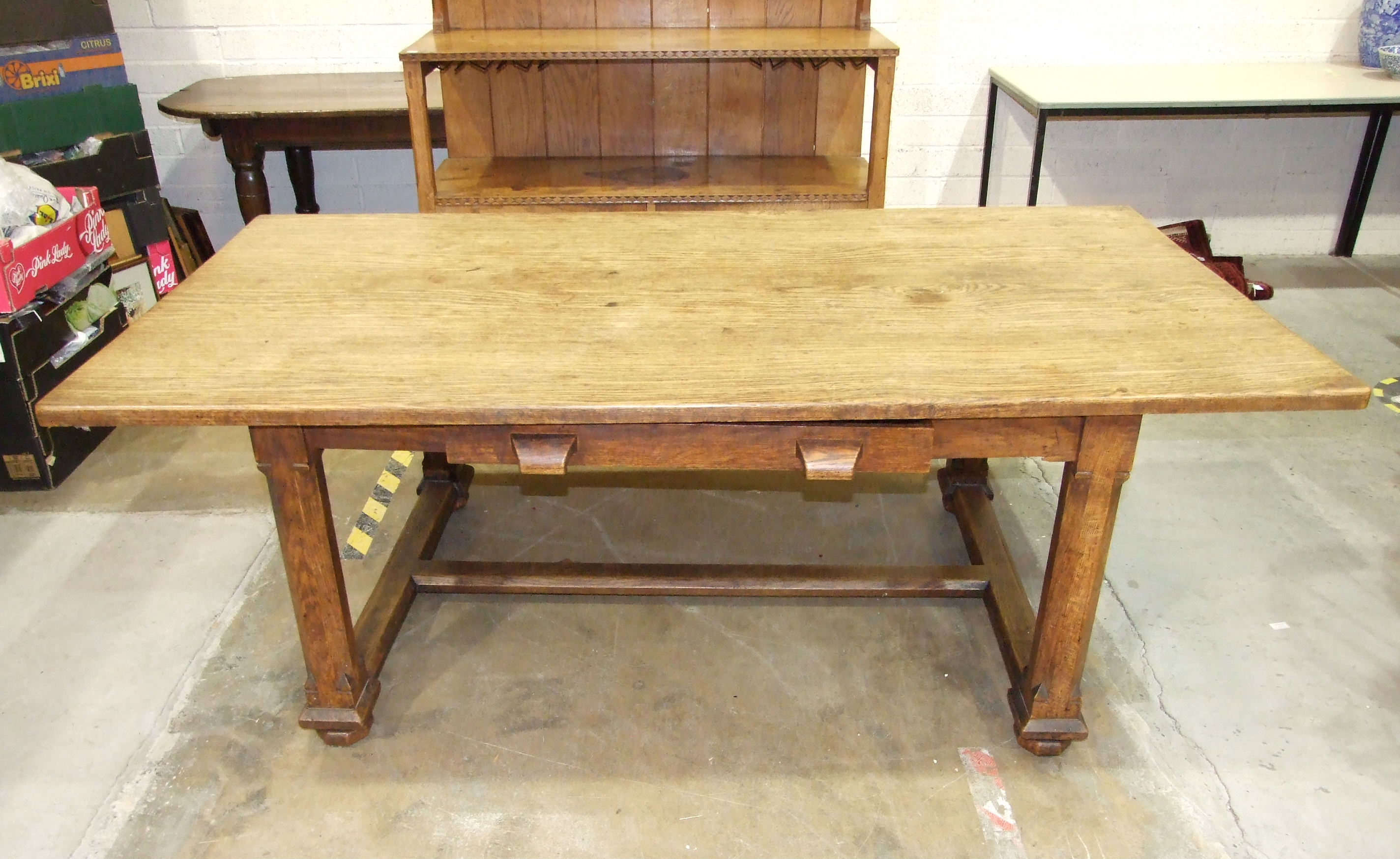 An early-20th century Arts & Crafts oak dining table, the plank top above a single frieze drawer, on