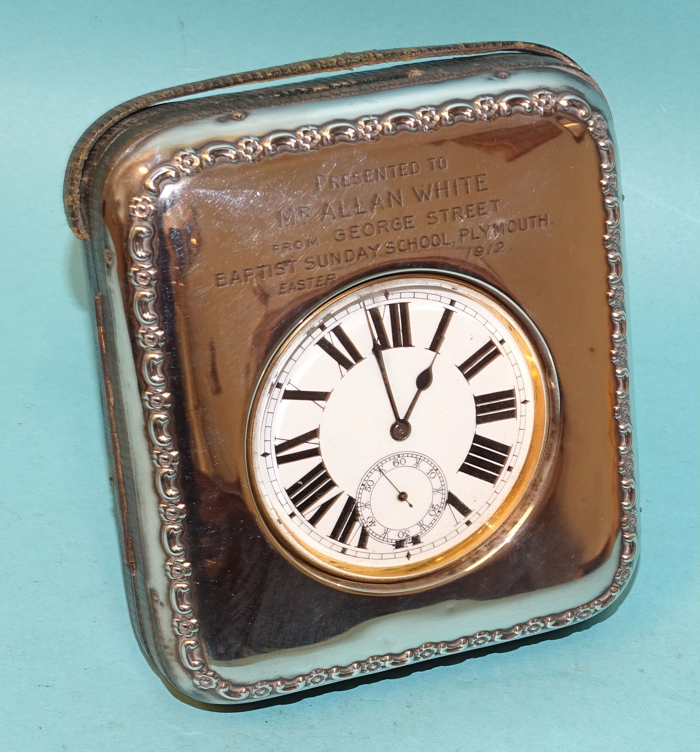 A silver watch holder with floral border and engraved inscription, Birmingham 1911, with steel-cased